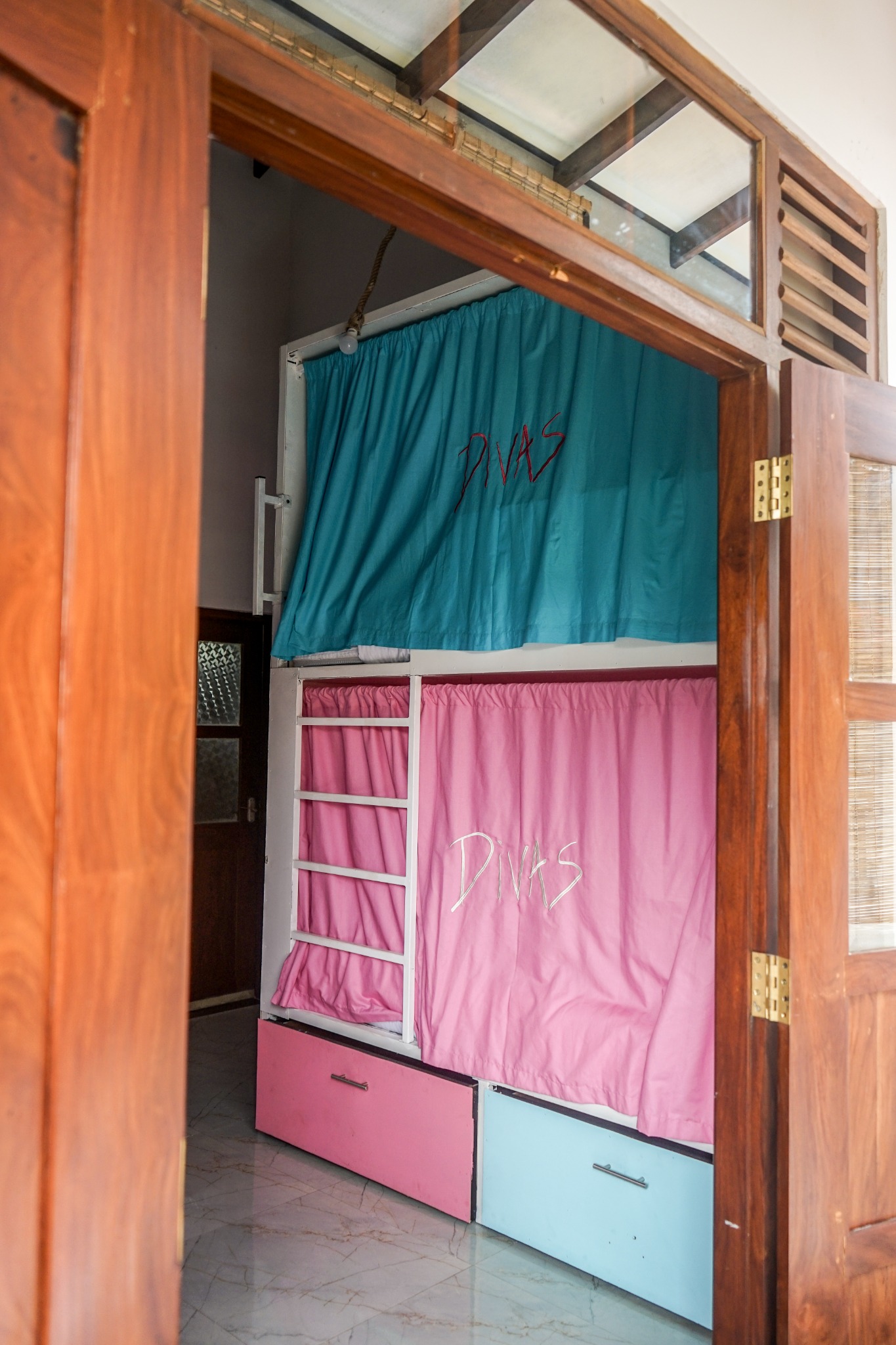 Bunk beds with privacy curtains and storage drawers seen from the doorway