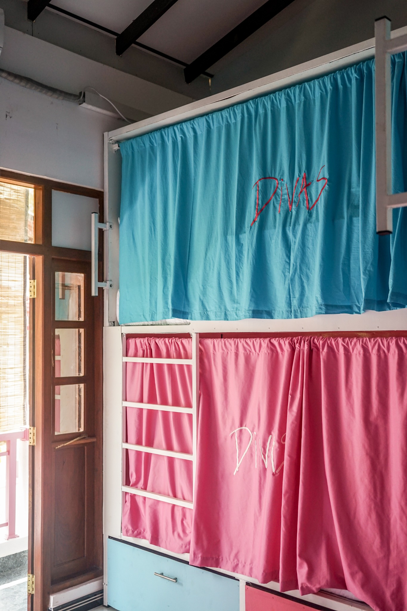 Close-up of upper aqua curtain and lower pink curtain on dorm bunks