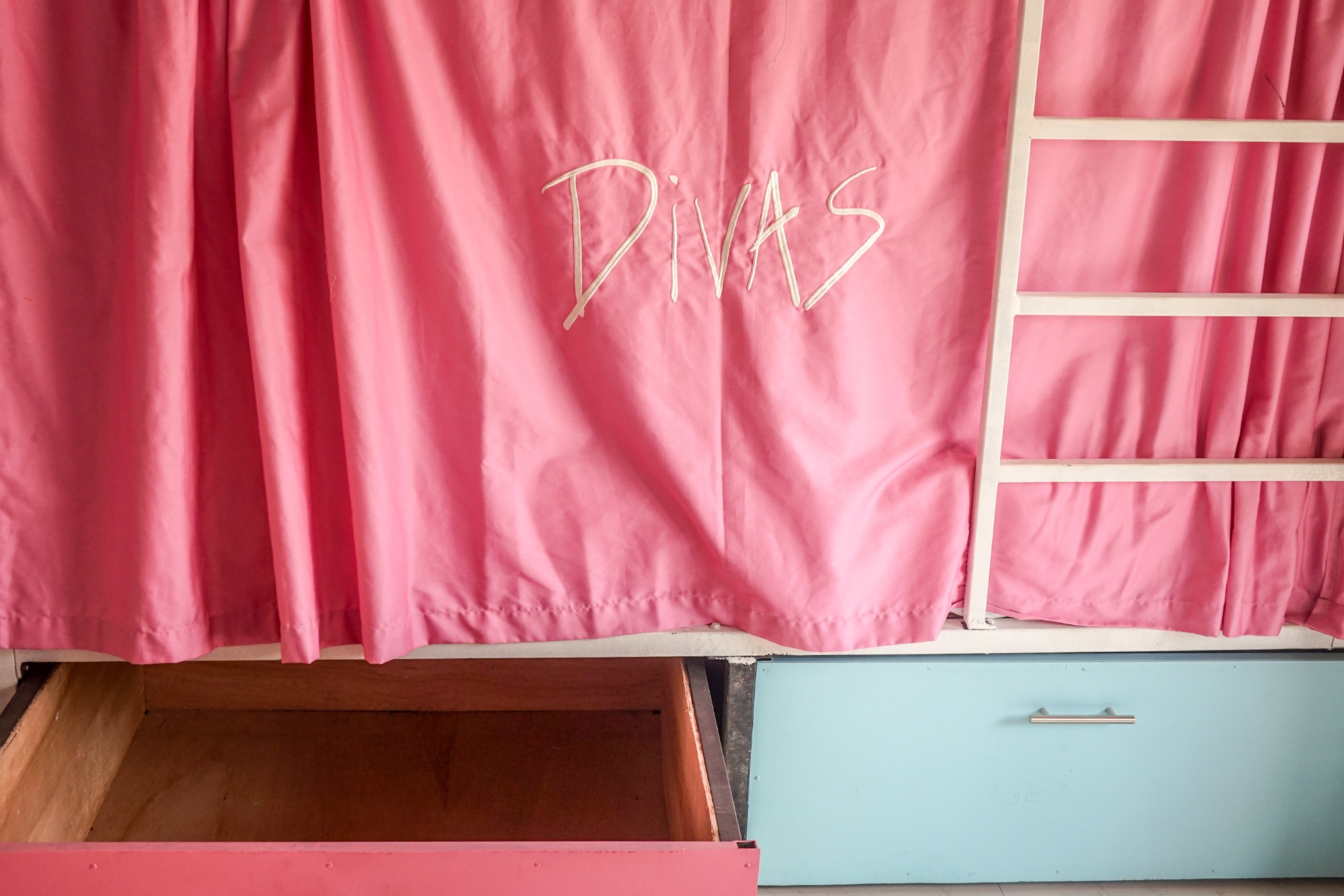 Pink dorm privacy curtain and open storage drawers
