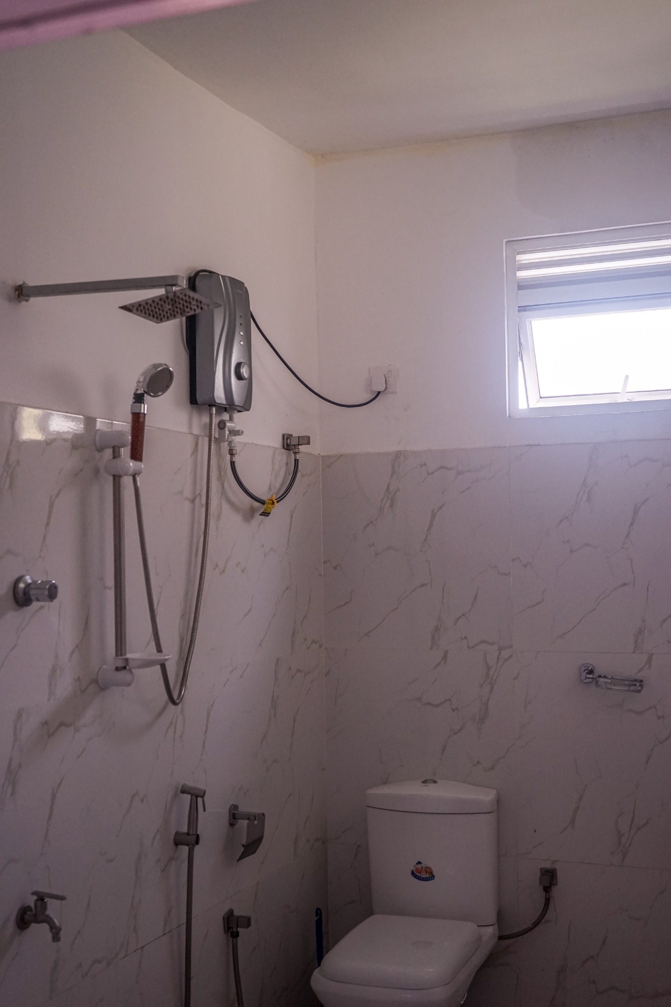 Bathroom with shower, white tiled walls, window and toilet