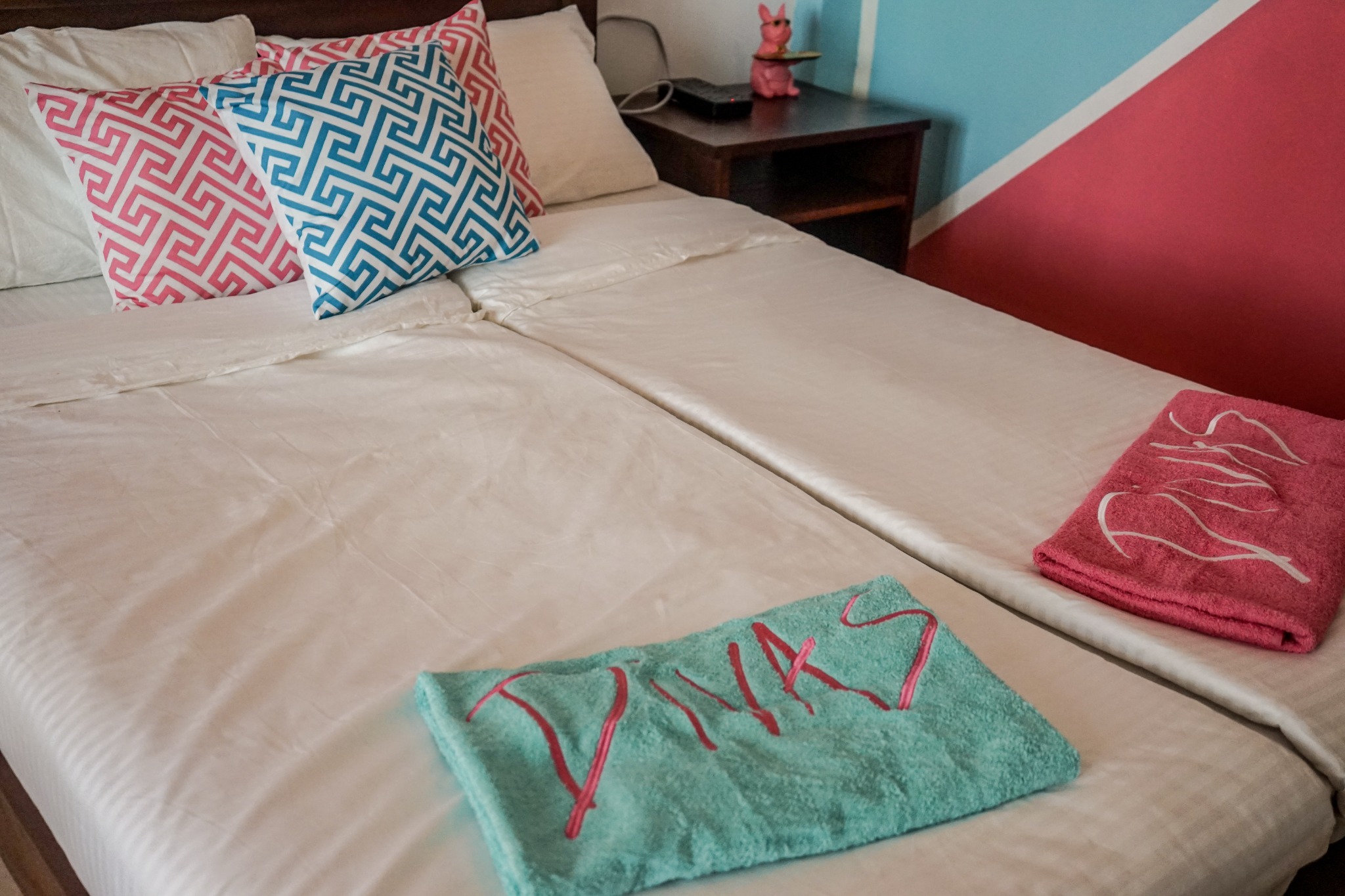 Fresh bedding with pink and aqua Divas towels laid out on the bed