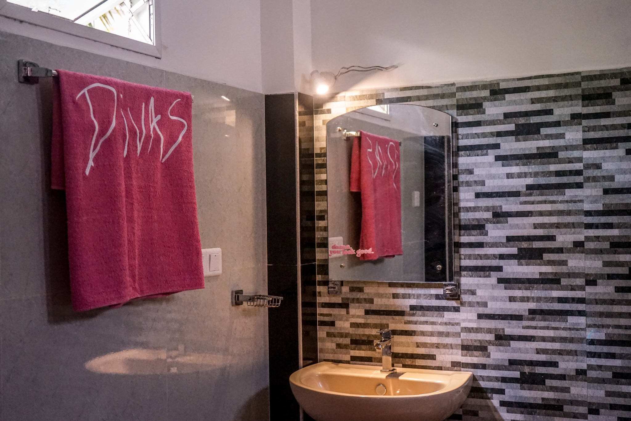 Bathroom sink, mirror, tiled wall and pink Divas towel